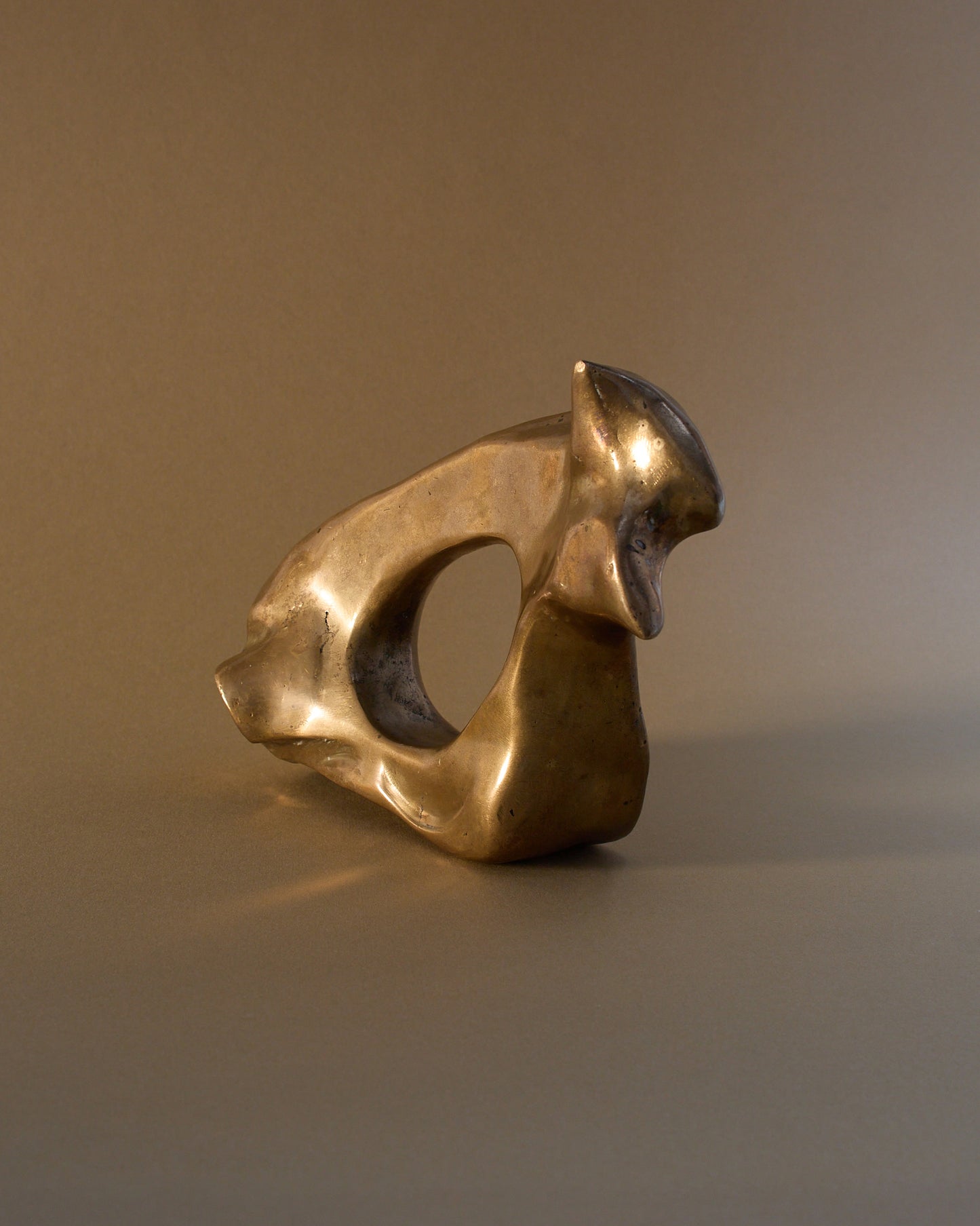Side view of abstract bronze sculpture by James Mercurin (c.1990s) — pierced centre, polished surface.