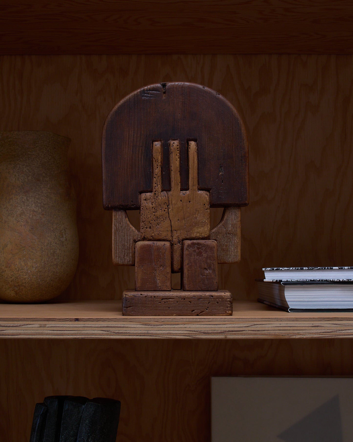 Wooden sculpture by Adolf Vallazza (1977) — shown on a shelf, among books and ceramics to provide scale.